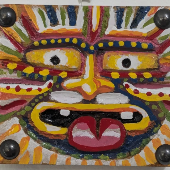 Earth Guardian,
Oil Enamel on Wood Painting,
3.5 H x 4 W x .75 in Critique of "Earth Guardian" by Art Ramon Art Ramon’s “Earth Guardian” bursts forth as an unapologetically vibrant celebration of primal energy and terrestrial vitality. The piece, carved into wood and painted with oil enamel, captures the essence of a mythical protector—bold, fierce, and deeply rooted in the earth’s essence. With its commanding gaze and intricate details, it conveys a dynamic interplay between raw artistic expression and symbolic storytelling. Composition and Form The composition centers on a mask-like figure, radiating a symmetrical balance of power and intensity. The exaggerated features—the large, staring eyes, the flaring nostrils, and the protruding tongue—immediately confront the viewer, demanding attention. These exaggerated elements are reminiscent of cultural masks used in rituals or ceremonies, giving the work a sense of timelessness and universality. The sharp, angular carvings contrast beautifully with the curves of the features, creating a dynamic rhythm that feels alive. The piece’s framing elements, accentuated by steel bolts, lend it a grounded, almost industrial feel, as though this guardian has transcended from myth to modernity. Color and Paint Application The palette of “Earth Guardian” is nothing short of explosive. A vivid array of yellows, reds, greens, and blues radiates outward from the central figure, evoking the richness and diversity of the natural world. The repeated dots and stripes create a sense of movement and rhythm, much like the pulsating energy of the earth itself. The glossiness of the oil enamel amplifies the colors, giving the piece a tactile, almost jewel-like quality. The layering of paint is deliberate yet spontaneous, echoing the raw, untamed nature of the earth while maintaining an underlying structure. Symbolism and Interpretation “Earth Guardian” embodies protection, fertility, and primal energy. The central figure's wide, unflinching eyes appear both vigilant and omniscient, a reminder of the earth’s enduring presence and its ability to watch over all life forms. The protruding tongue, often symbolic of defiance or warning in various cultures, further reinforces the guardian's protective and assertive role. The radiating patterns surrounding the face suggest growth and life energy, reminiscent of the sun’s rays or the rings of a tree. This visual metaphor ties the piece to the cycles of nature—birth, growth, decay, and rebirth—positioning the “Earth Guardian” as a timeless overseer of these processes. Craftsmanship and Concept The combination of carving and painting is masterfully executed. The tactile depth of the wood adds dimensionality, while the meticulous paintwork infuses the piece with vibrancy. The deliberate use of steel bolts as a structural and decorative element bridges the organic and the industrial, grounding the piece in the present while evoking ancient traditions. The conceptual power of “Earth Guardian” lies in its ability to resonate across cultures and time periods. It is a protector not just of a specific realm but of universal ideas—nature’s vitality, resilience, and interconnectedness. This universality makes the piece accessible while retaining its deeply personal and spiritual essence. Conclusion Art Ramon’s “Earth Guardian” is a triumphant fusion of tradition and innovation, harnessing the raw energy of the earth while celebrating humanity’s role as both creator and steward. Its bold colors, striking symmetry, and layered symbolism make it a standout piece that invites both introspection and admiration. As a guardian of the natural world, this work reminds us of our deep connection to the earth and its enduring spirit.